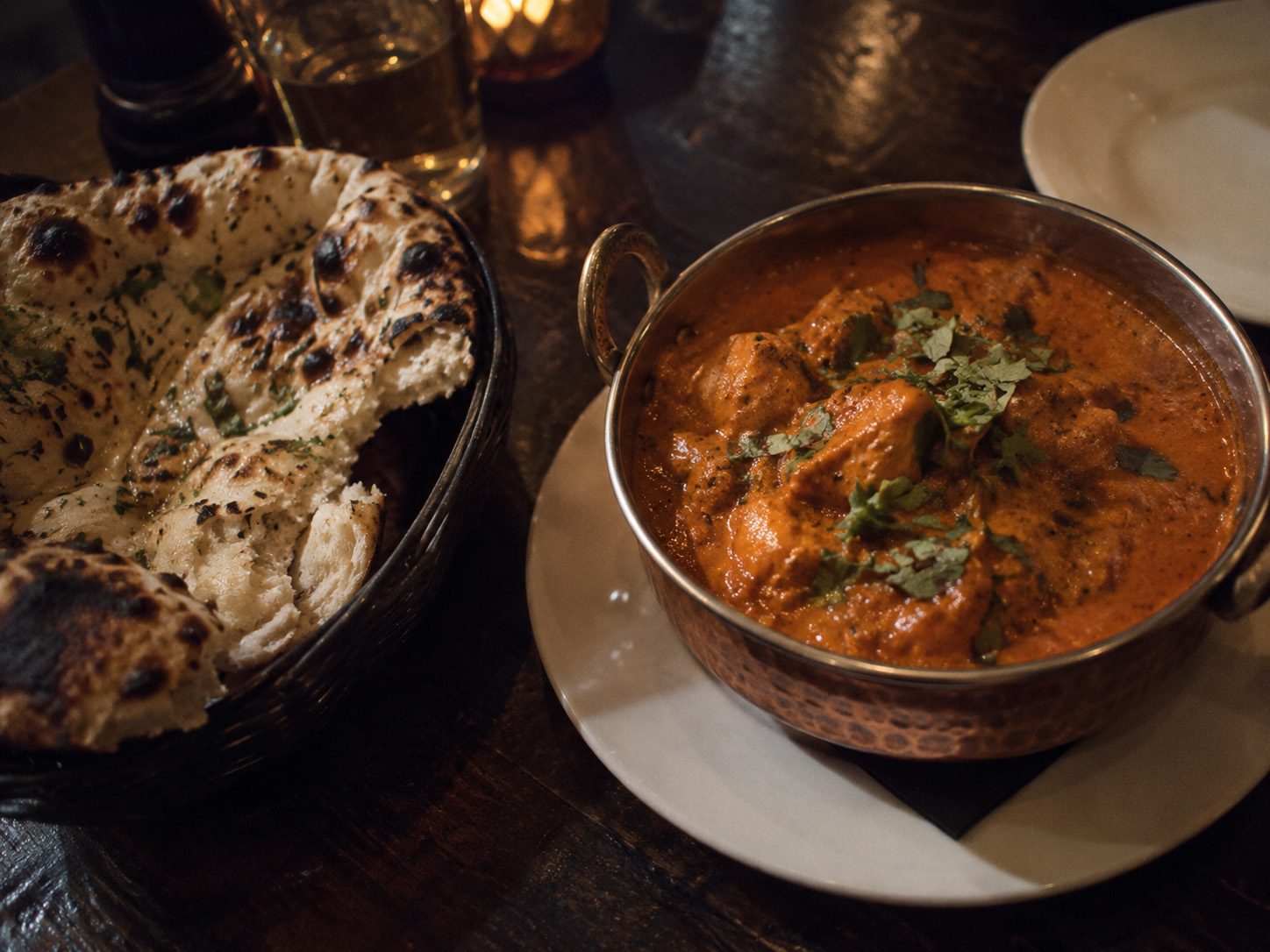 Concept image, generated: chicken tikka masala in a copper dish with charred naan